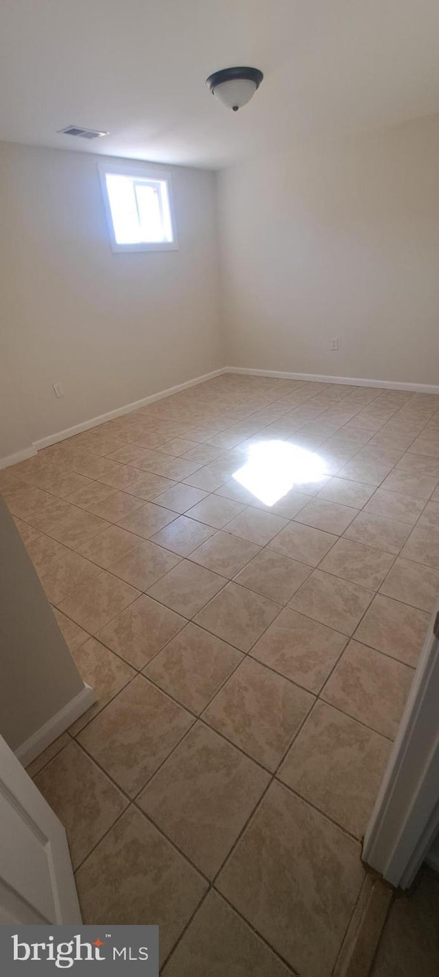 spare room featuring light tile patterned floors, visible vents, and baseboards