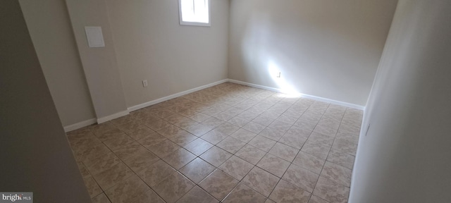 spare room with baseboards and light tile patterned floors