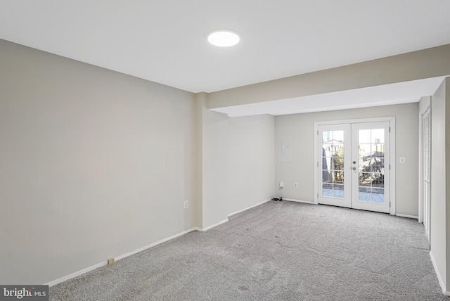 spare room featuring french doors, carpet flooring, and baseboards