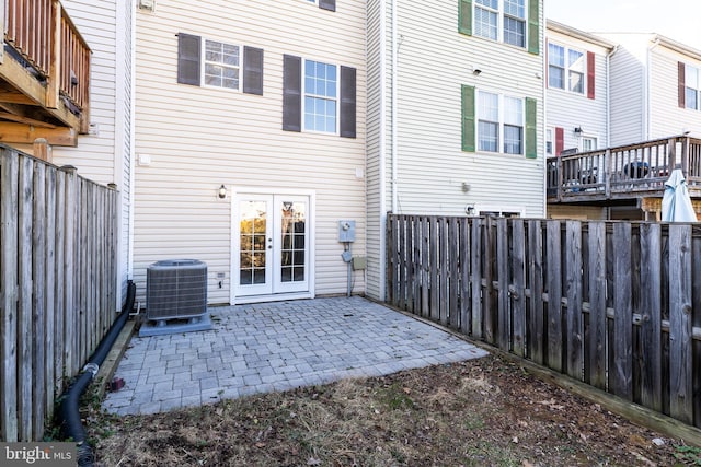 rear view of house with cooling unit, french doors, a fenced backyard, and a patio