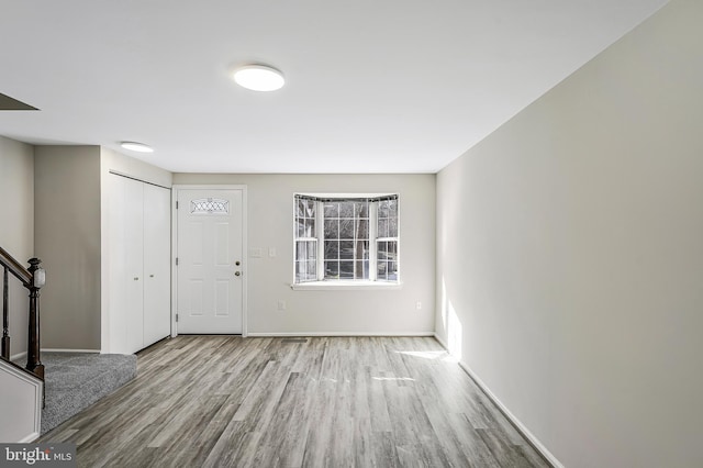 entryway with stairway, wood finished floors, and baseboards