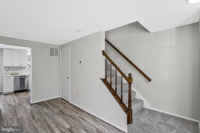 stairs featuring wood finished floors, visible vents, and baseboards