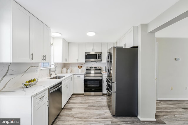 kitchen with appliances with stainless steel finishes, white cabinetry, and a sink