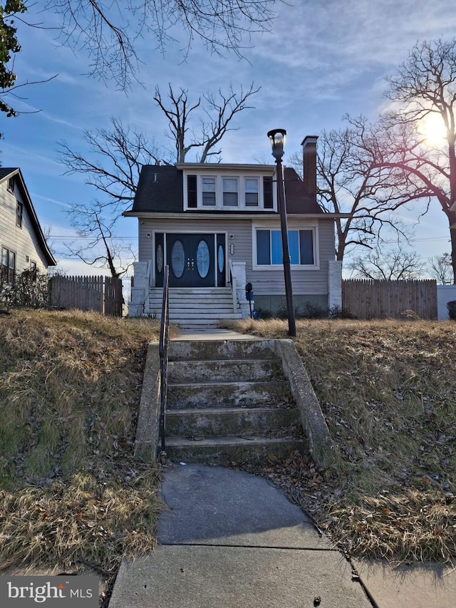 bungalow featuring a chimney and fence