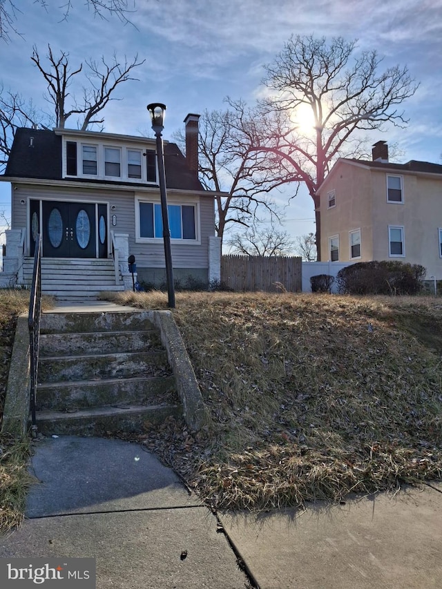 view of front of property with a chimney and fence