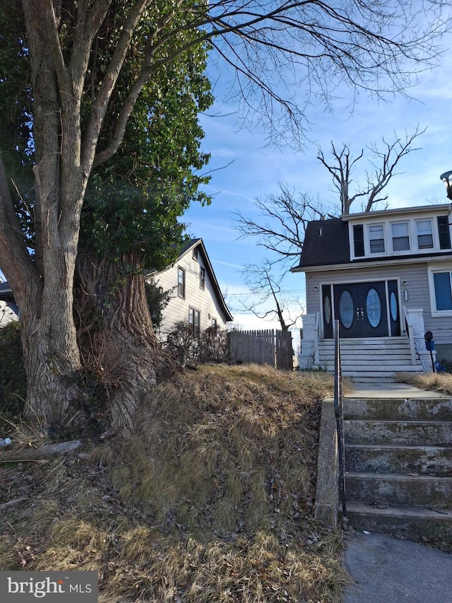 view of front of house with roof with shingles and fence