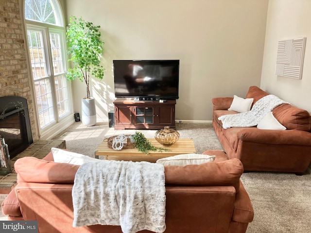 living room with baseboards, a glass covered fireplace, and carpet flooring