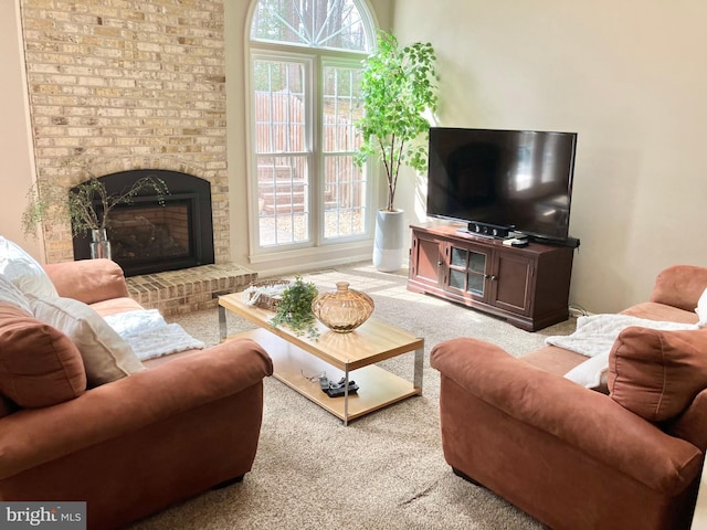 living area featuring a brick fireplace, plenty of natural light, and carpet