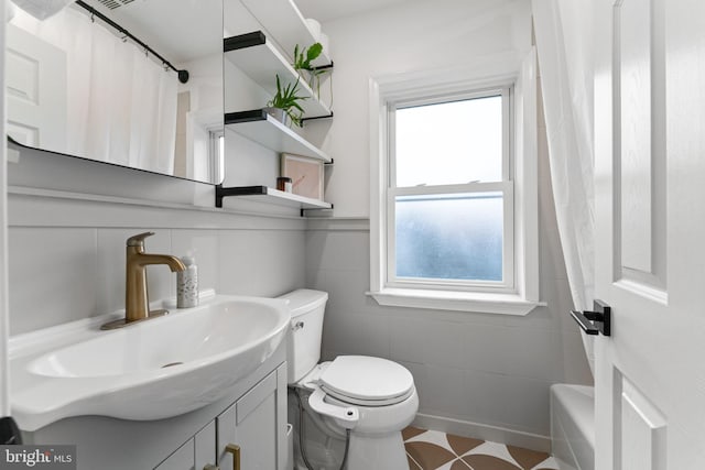 bathroom featuring wainscoting, a healthy amount of sunlight, vanity, and toilet