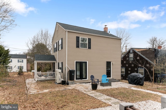 rear view of house featuring entry steps, a shingled roof, and a chimney