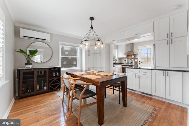 dining space featuring baseboards, light wood-style flooring, crown molding, a chandelier, and a wall mounted AC