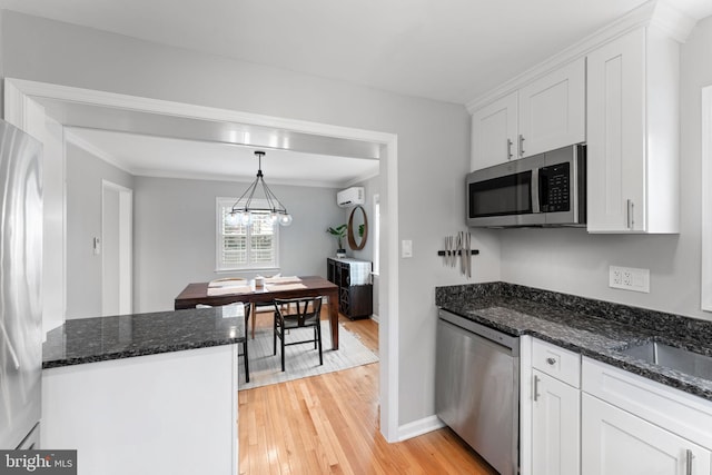 kitchen with light wood-style floors, white cabinetry, stainless steel appliances, and pendant lighting