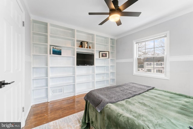 bedroom featuring visible vents, wood finished floors, a ceiling fan, and crown molding