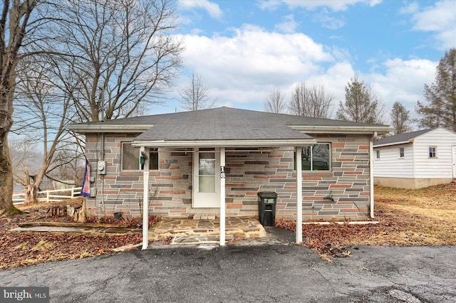 ranch-style house with stone siding and roof with shingles