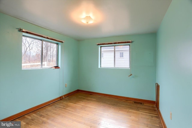 unfurnished room with light wood finished floors, baseboards, and visible vents