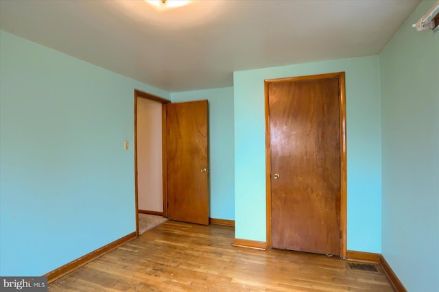 unfurnished bedroom with a closet, baseboards, and wood finished floors