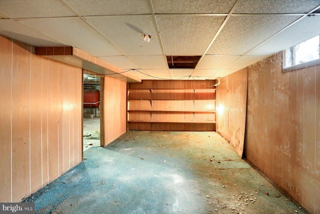 below grade area with a paneled ceiling and wood walls