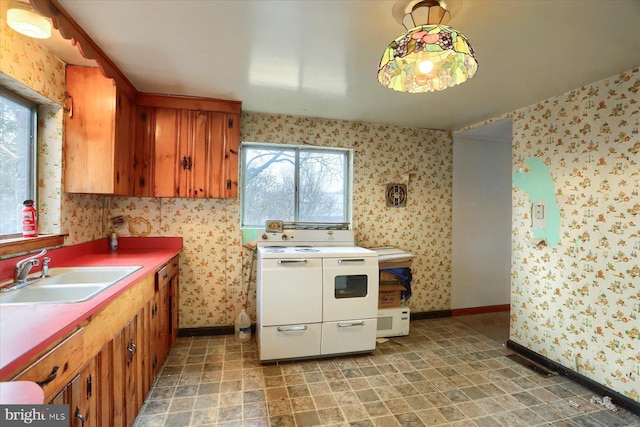 kitchen featuring brown cabinets, a sink, double oven range, baseboards, and wallpapered walls