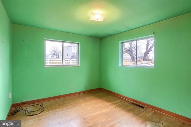 spare room featuring baseboards, visible vents, and hardwood / wood-style floors