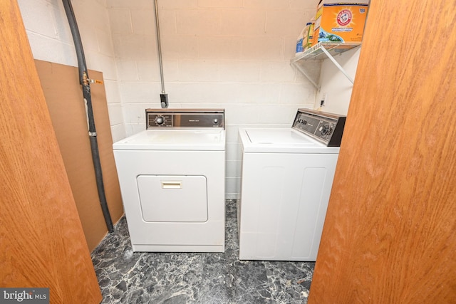 clothes washing area with laundry area, concrete block wall, and washer and dryer