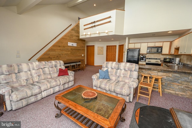 living area featuring light carpet, wooden walls, high vaulted ceiling, and beamed ceiling