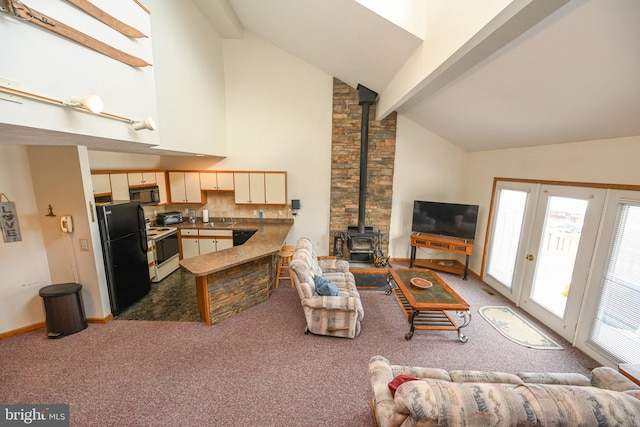 living room featuring high vaulted ceiling, baseboards, beam ceiling, dark colored carpet, and a wood stove