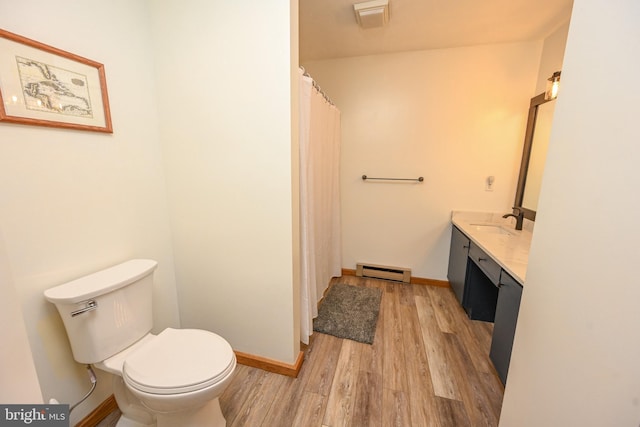 bathroom with a baseboard radiator, toilet, wood finished floors, vanity, and baseboards