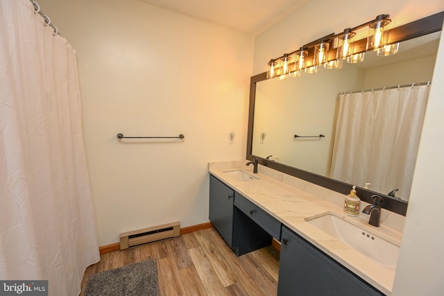 bathroom featuring a baseboard heating unit, a sink, baseboards, and wood finished floors