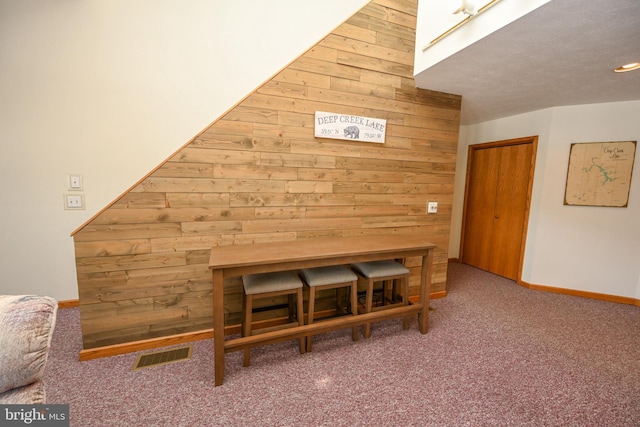 unfurnished dining area featuring wooden walls, carpet floors, a skylight, visible vents, and baseboards