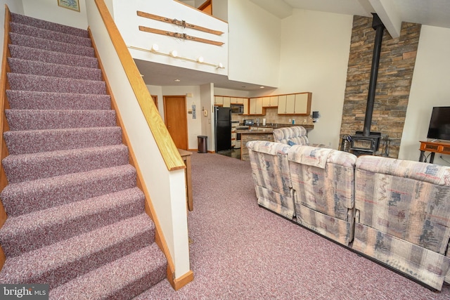 stairway with high vaulted ceiling, carpet, a wood stove, and beamed ceiling