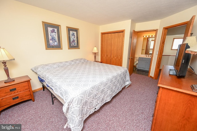 carpeted bedroom with ensuite bath, baseboards, and a closet