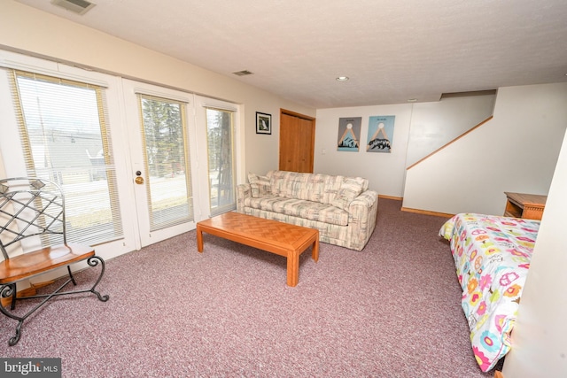 living area with a textured ceiling, carpet, visible vents, and baseboards