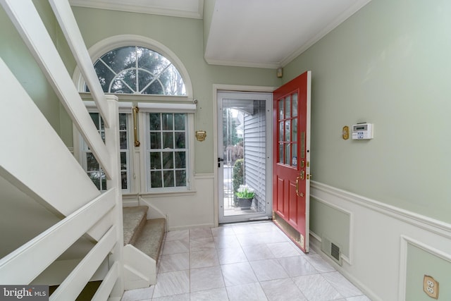 entrance foyer featuring tile patterned flooring, crown molding, stairway, and visible vents