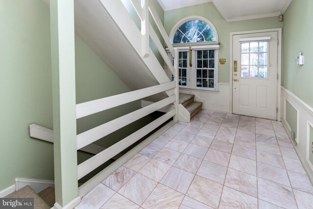 foyer entrance featuring stairway, a wainscoted wall, and ornamental molding