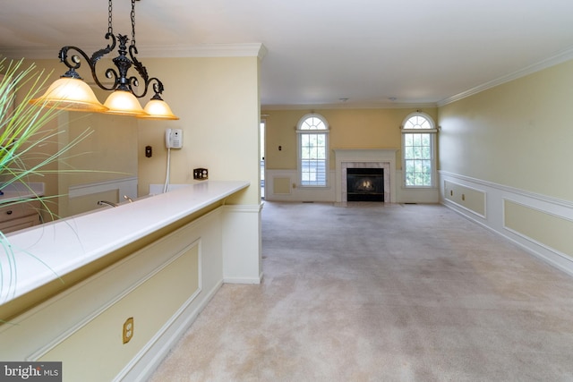 kitchen featuring light colored carpet, pendant lighting, crown molding, and a decorative wall