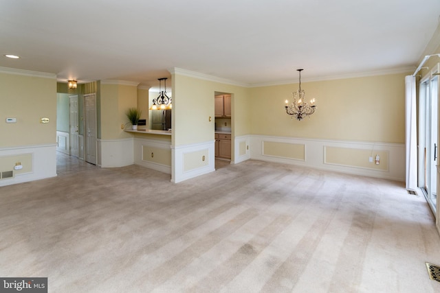 unfurnished room featuring visible vents, wainscoting, crown molding, light colored carpet, and a chandelier