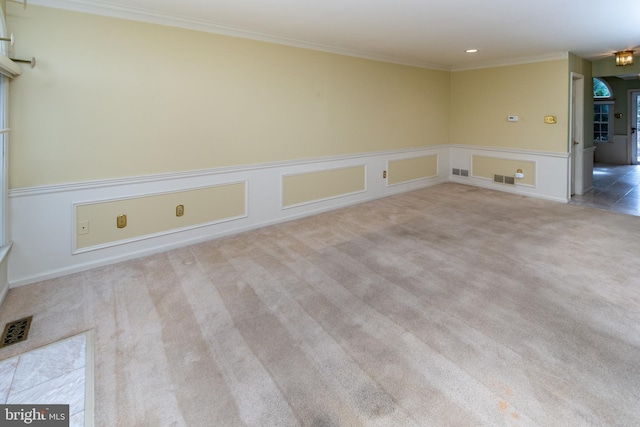 carpeted spare room featuring visible vents, a wainscoted wall, and crown molding