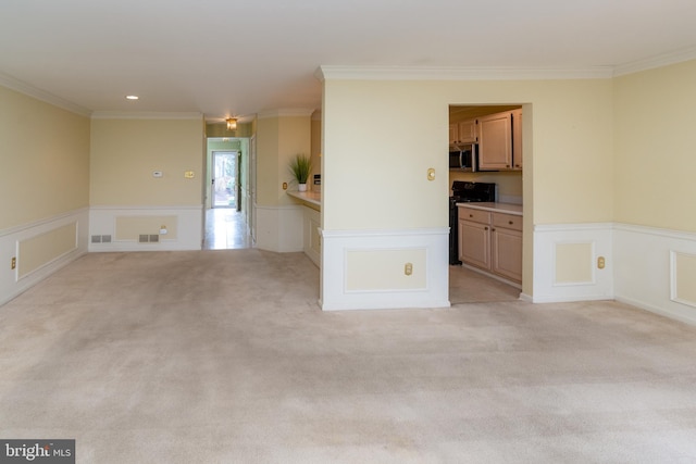 unfurnished room with ornamental molding, visible vents, a wainscoted wall, and light carpet