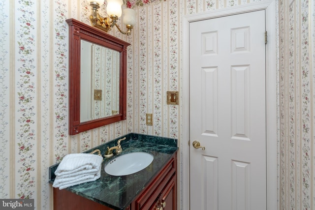 half bathroom featuring vanity and wallpapered walls