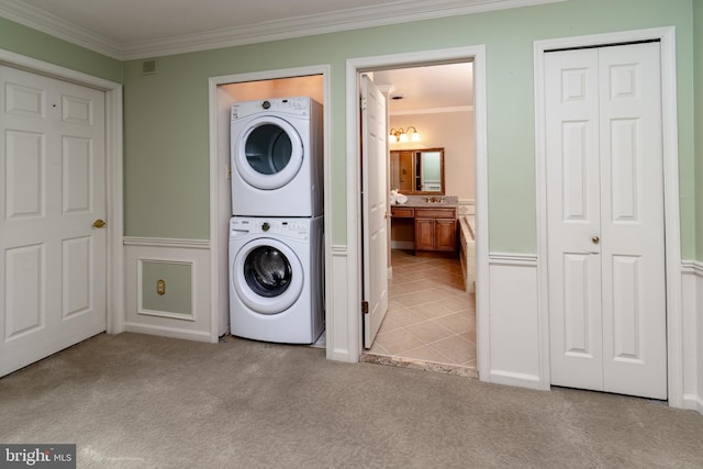 laundry area featuring laundry area, stacked washer and dryer, ornamental molding, and light carpet