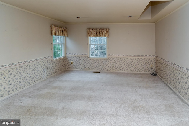 empty room featuring a wainscoted wall, ornamental molding, carpet flooring, and wallpapered walls