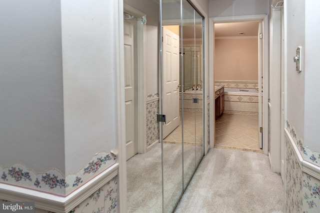 hallway featuring light tile patterned floors, light colored carpet, and crown molding