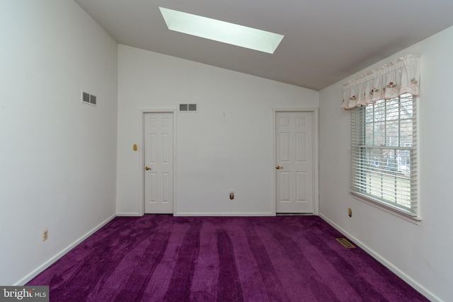 carpeted spare room with lofted ceiling with skylight, baseboards, and visible vents