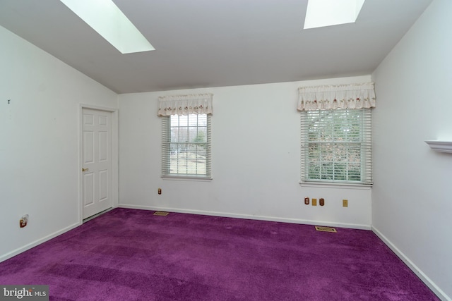 unfurnished room featuring baseboards, lofted ceiling with skylight, visible vents, and carpet flooring