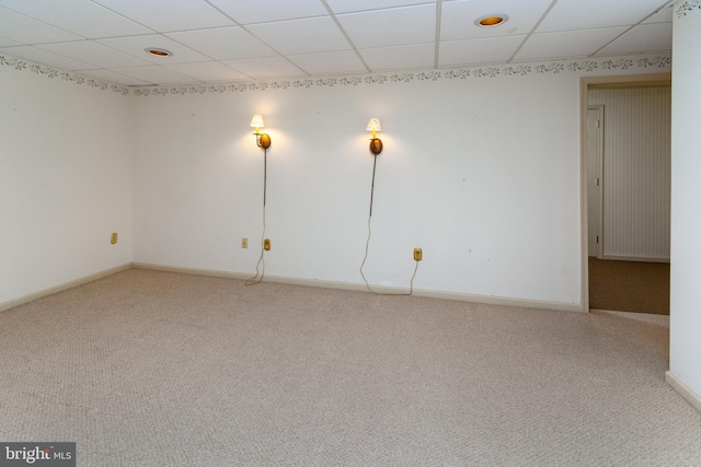 carpeted spare room featuring a paneled ceiling and baseboards