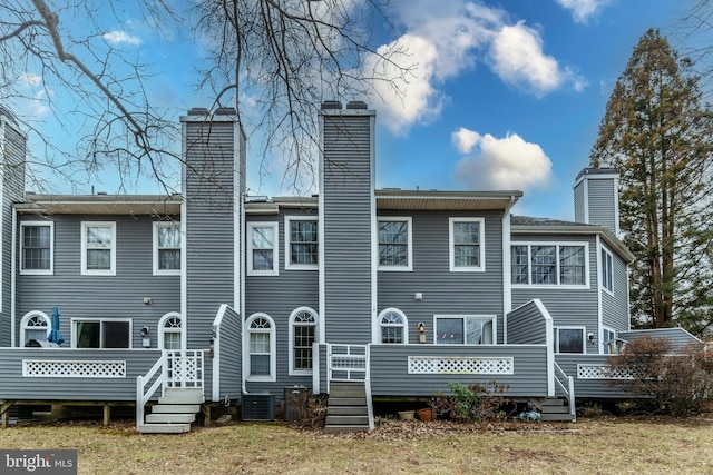 back of property with central AC unit, a chimney, and a deck