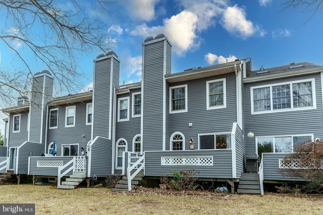 rear view of property with a wooden deck, a lawn, and a chimney