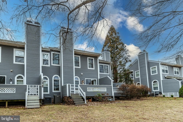 rear view of house featuring a wooden deck, a yard, cooling unit, and a chimney