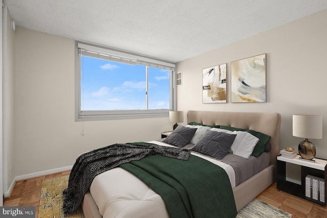 bedroom with a textured ceiling, visible vents, and baseboards