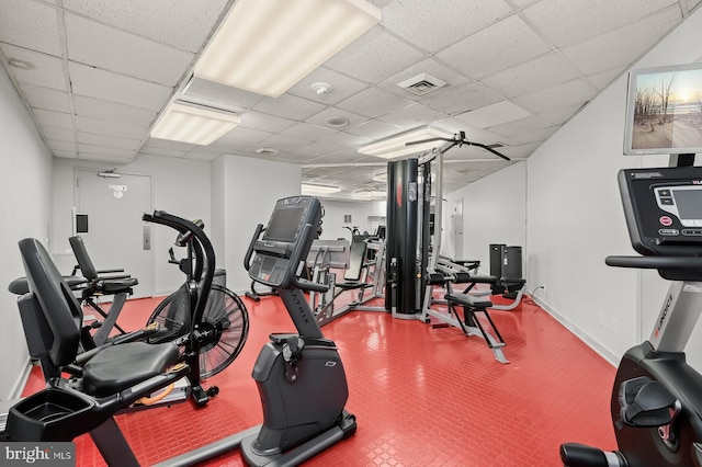 exercise room featuring a paneled ceiling, visible vents, and baseboards